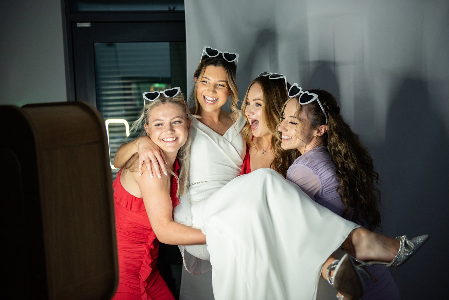 Bride laughing with friends wearing heart-shaped sunglasses